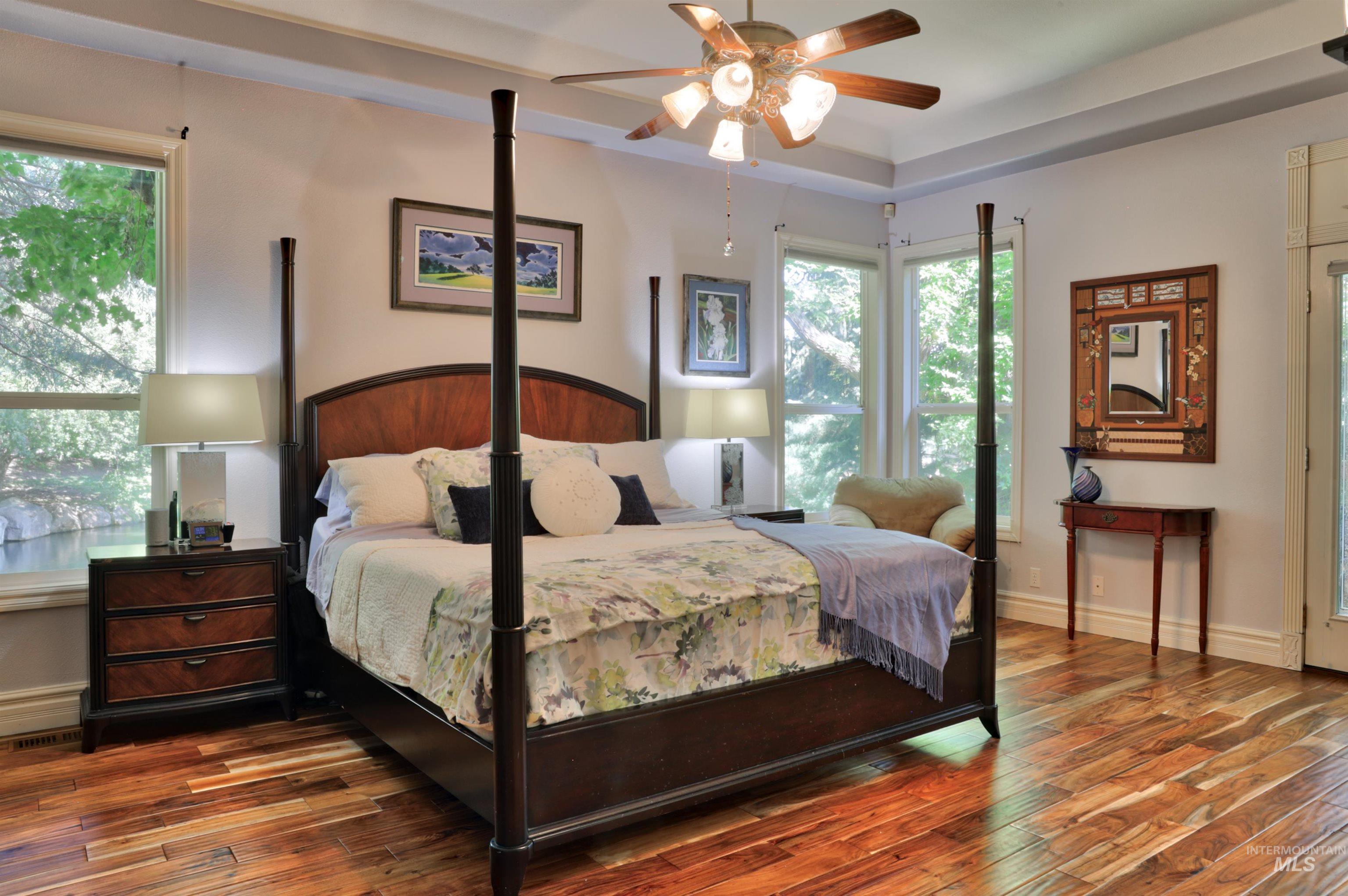 Wood-finish flooring and multiple windows framing exterior greenery