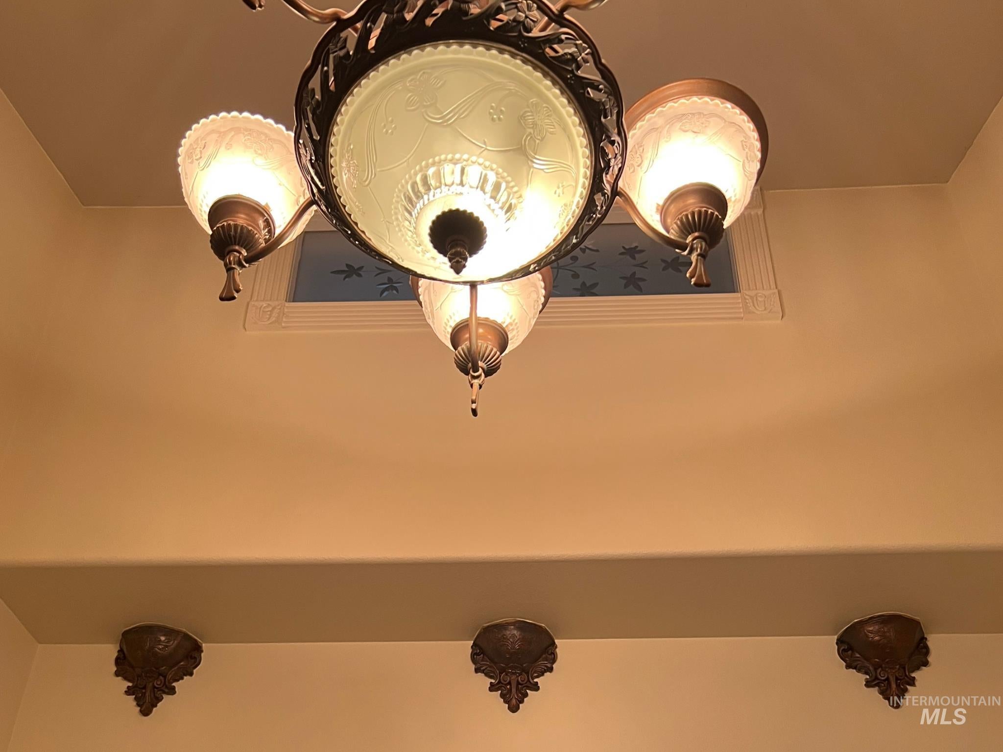 Ornate chandelier with four frosted glass shades and decorative metalwork