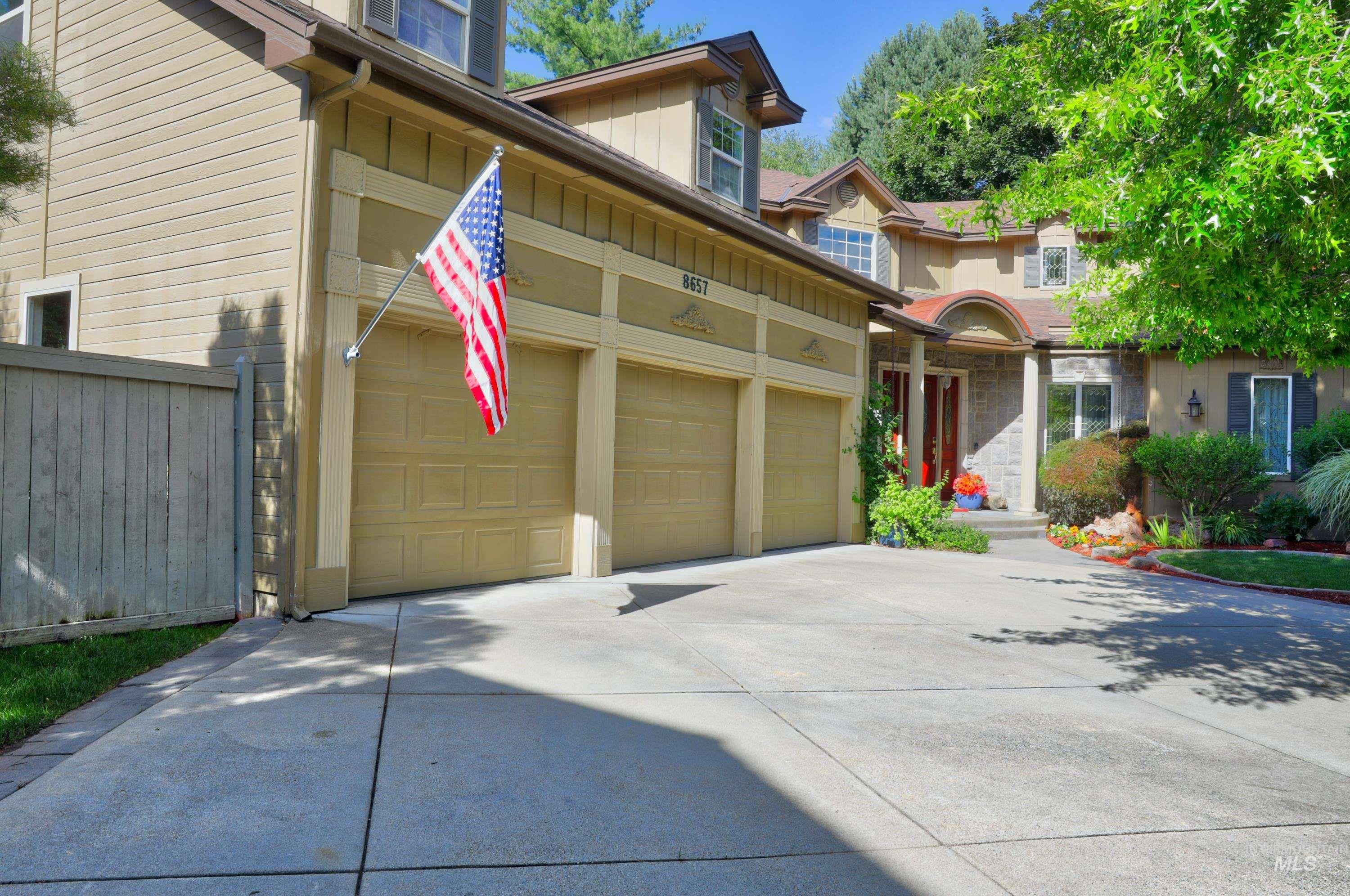Multi-level residence featuring a three-car garage and a concrete driveway