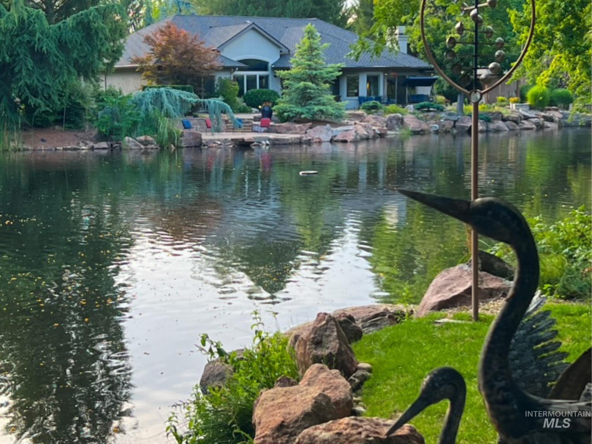 Waterfront property featuring a stone rockery, lush perimeter landscaping, and a patio area