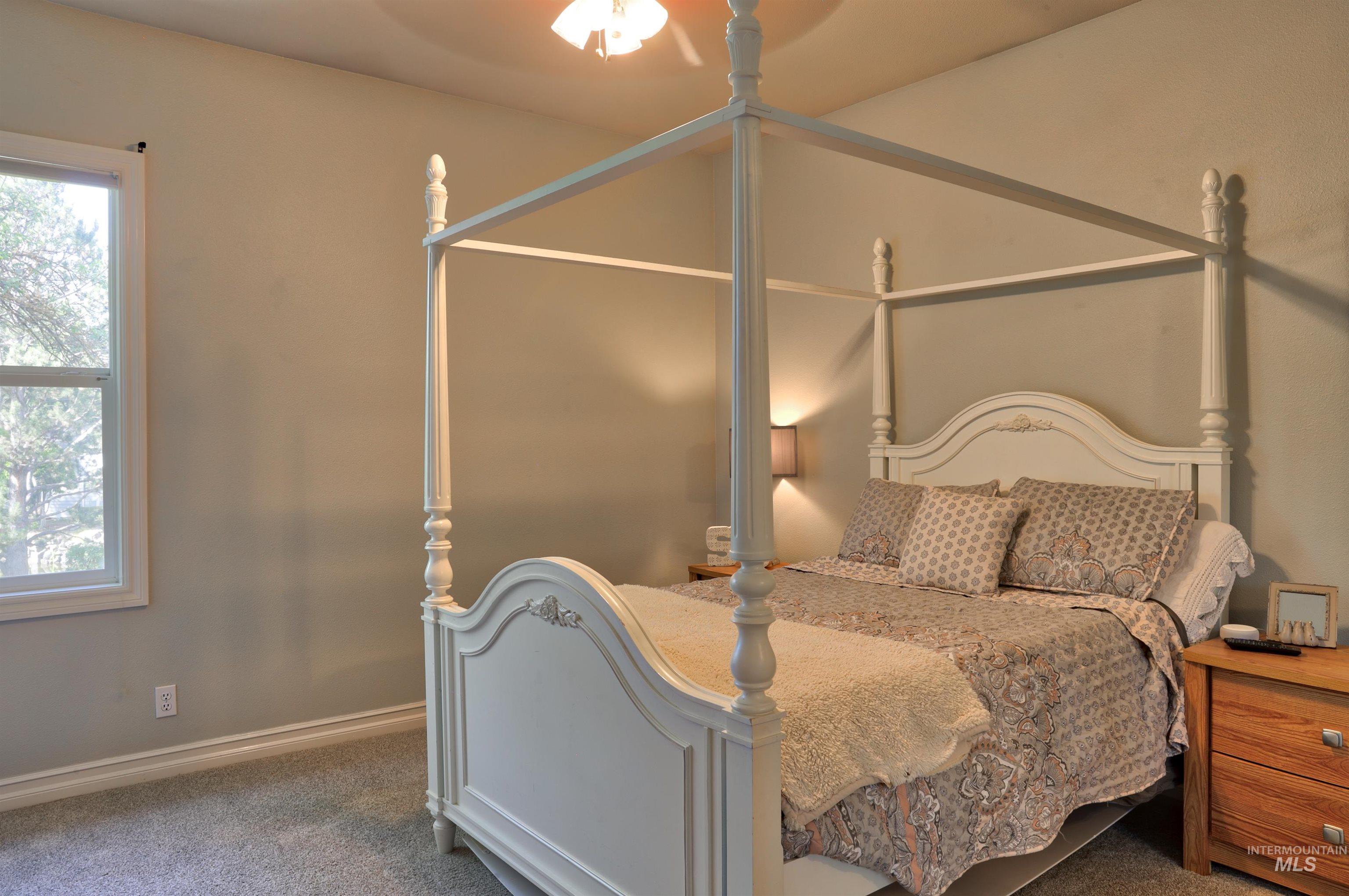Bedroom featuring light gray walls, gray carpet flooring, white trim, and a window with white casing