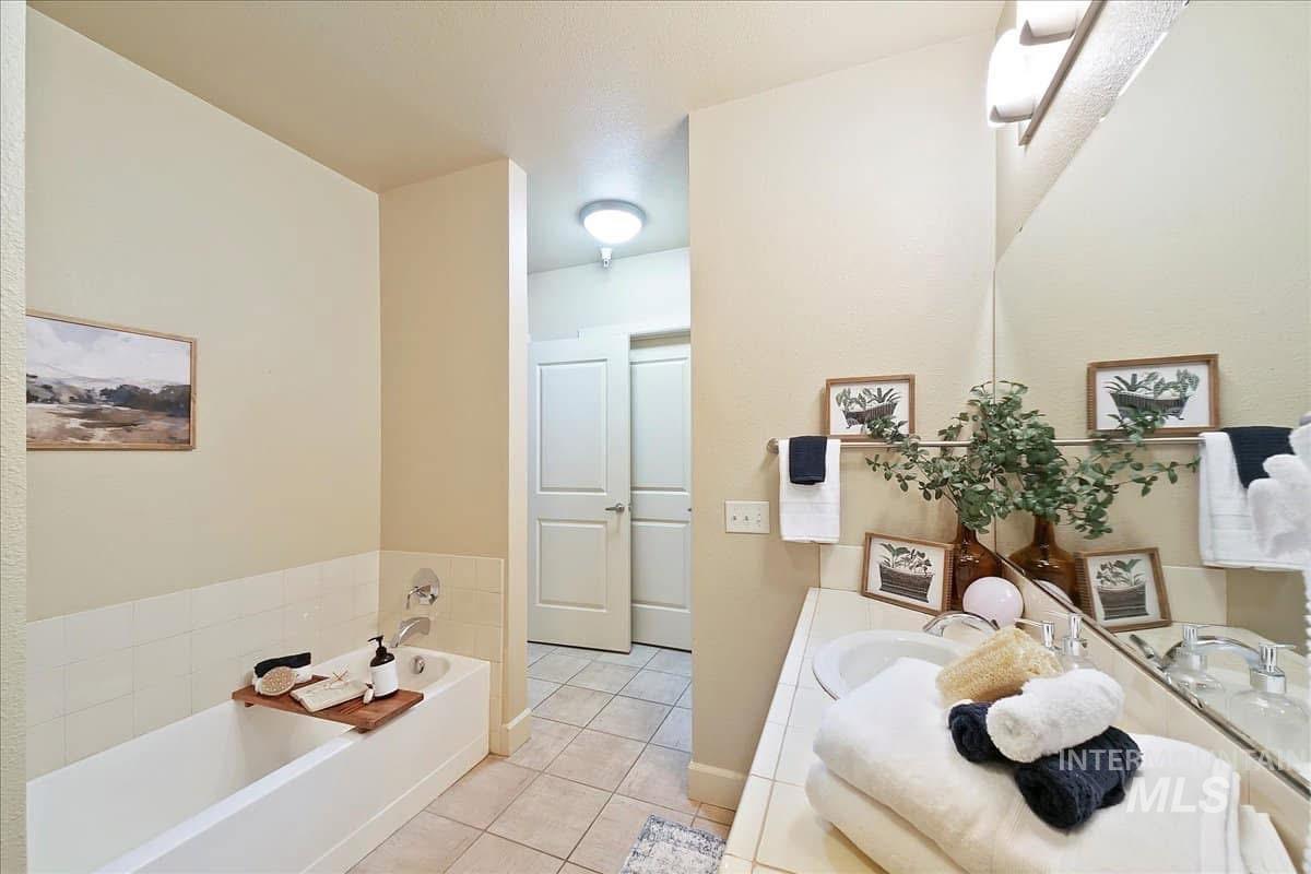 Bathroom with double vanity, a garden tub, and light tile patterned floors