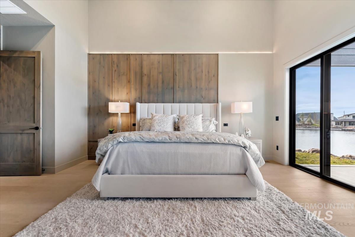 Bedroom featuring access to exterior, wood finished floors, and a water view