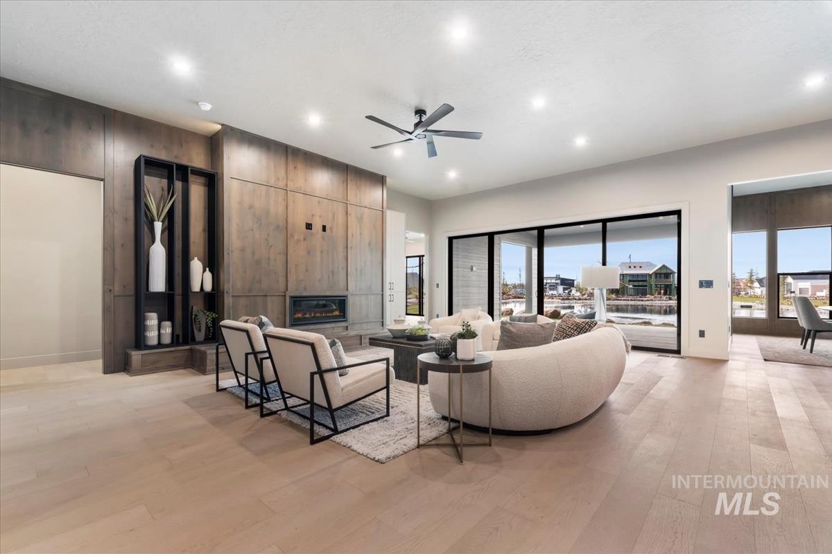 Living area featuring a ceiling fan, a fireplace, light wood-style flooring, recessed lighting, and wood walls