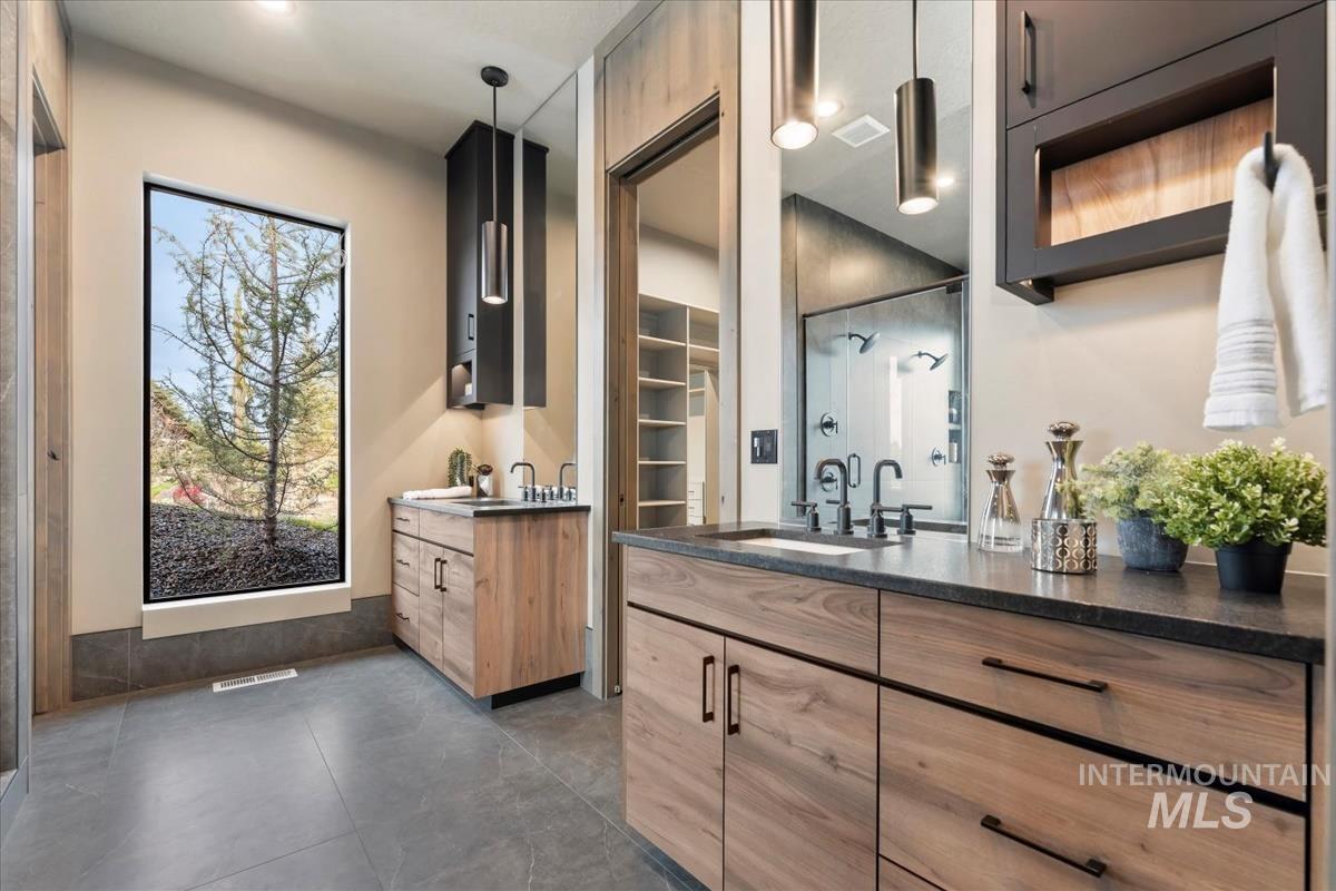 Full bathroom featuring two vanities, a spacious closet, and a stall shower