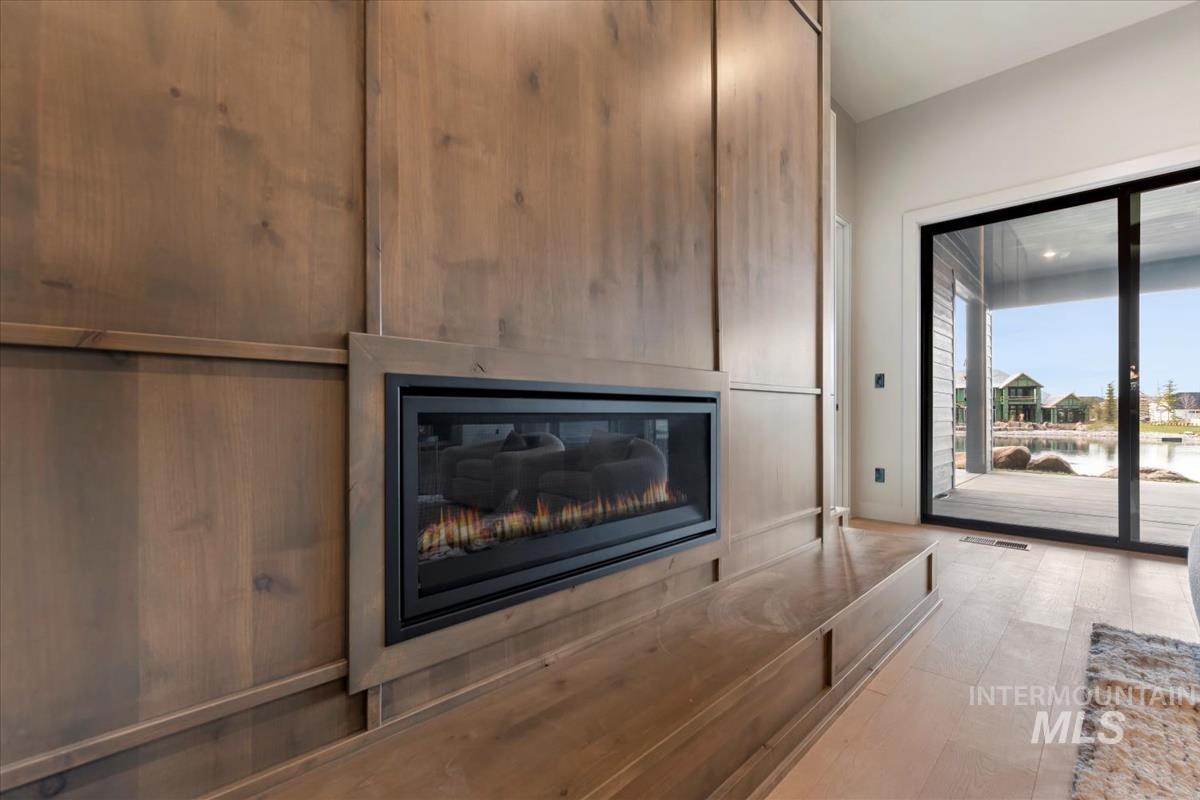 Detailed view of wood finished floors, nearby water, and a glass covered fireplace