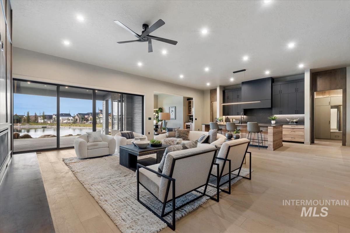 Living area with a water view, ceiling fan, recessed lighting, and light wood finished floors