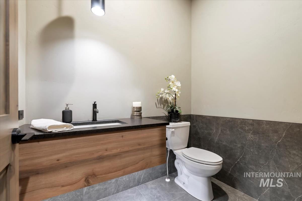 Bathroom featuring tile walls, vanity, a wainscoted wall, and tile patterned flooring