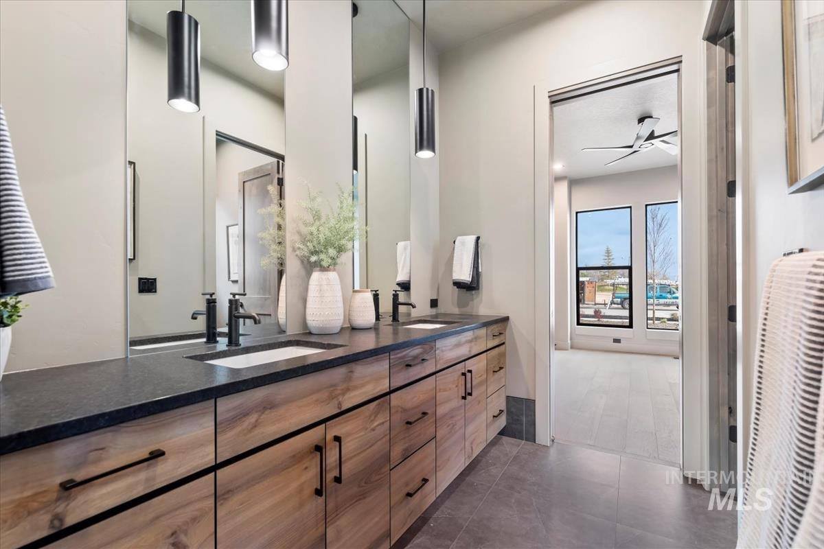 Full bathroom featuring double vanity, a ceiling fan, and dark tile patterned flooring