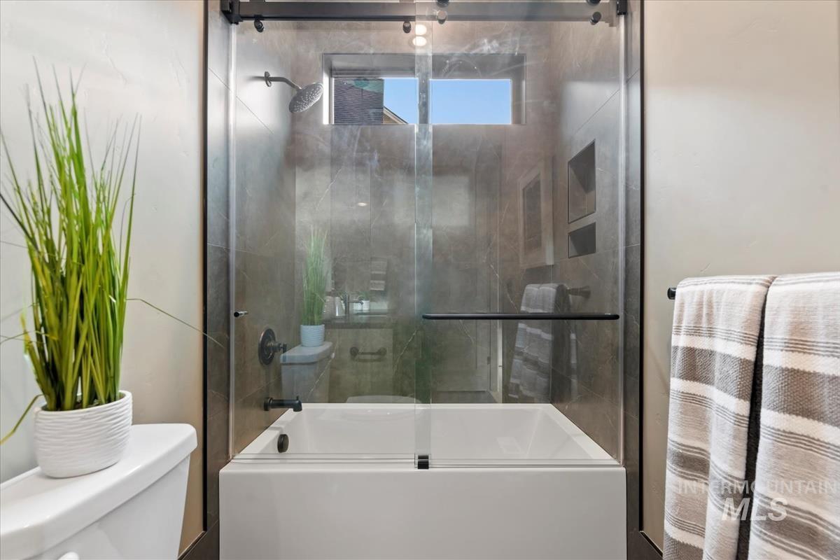 Bathroom with combined bath / shower with glass door and toilet