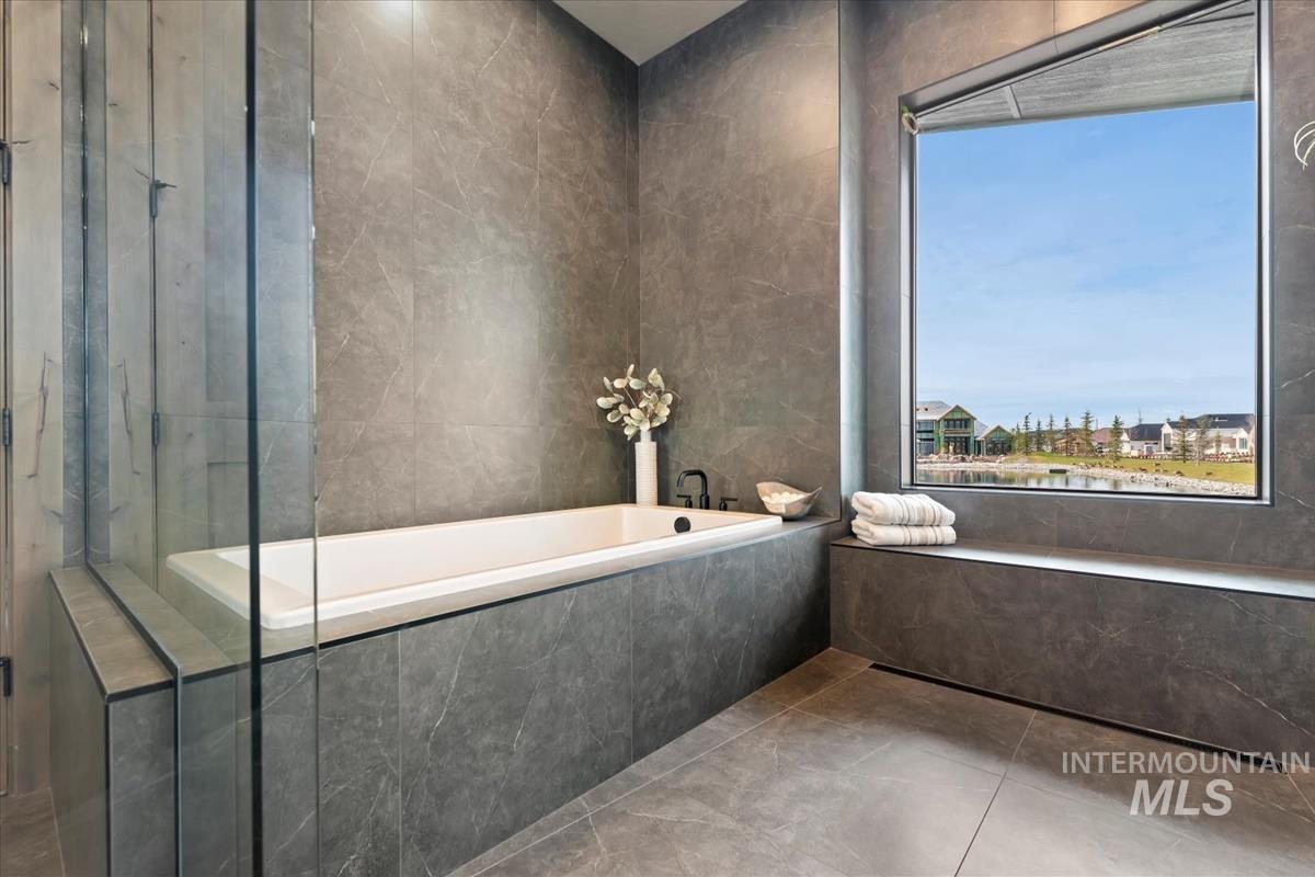Bathroom featuring a relaxing tiled tub, tile walls, and tile patterned floors