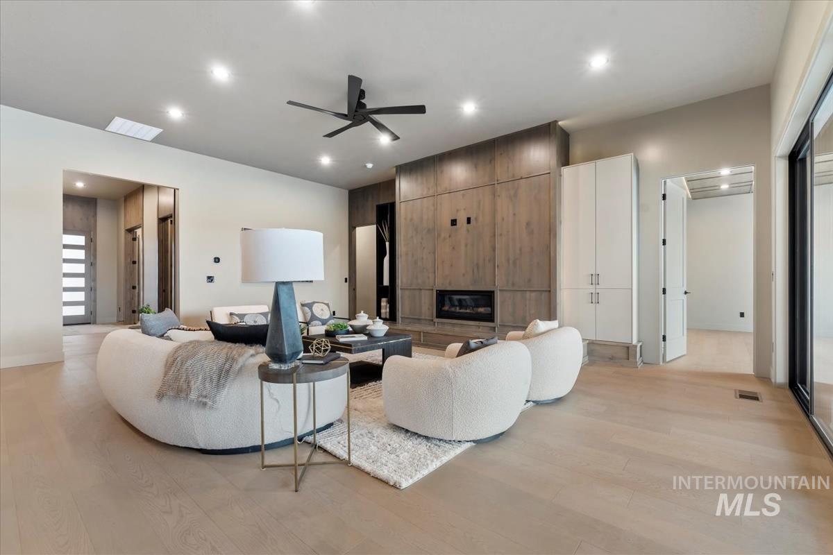 Living area featuring a ceiling fan, a fireplace, light wood-type flooring, and recessed lighting
