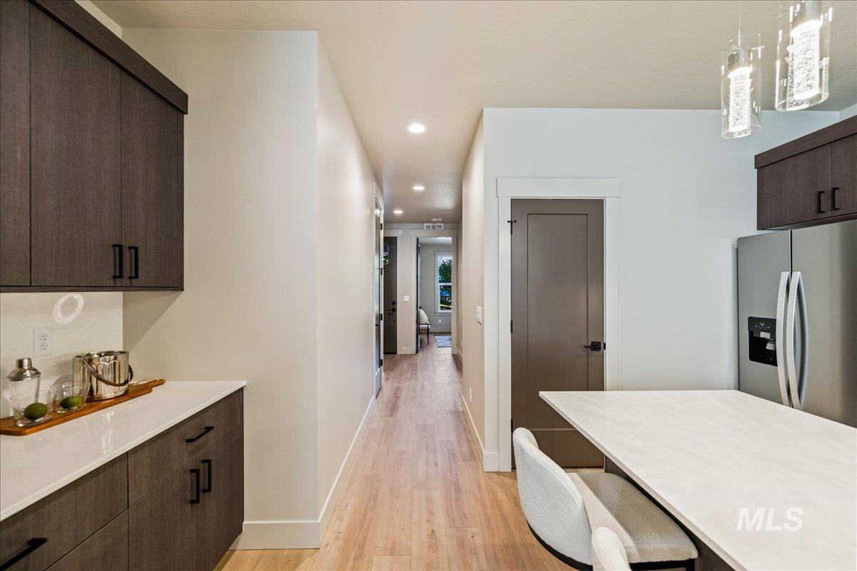Kitchen with dark brown cabinets, stainless steel refrigerator with ice dispenser, modern cabinets, recessed lighting, and light wood finished floors