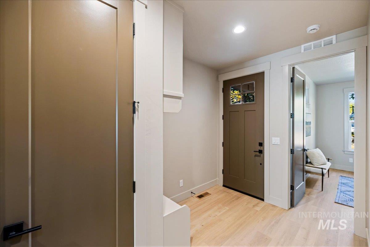 Foyer with light wood finished floors and recessed lighting