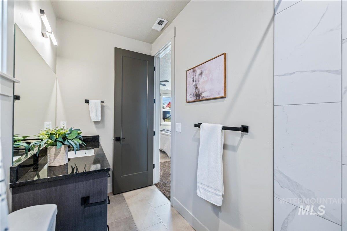 Ensuite bathroom featuring double vanity, light tile patterned flooring, and light carpet