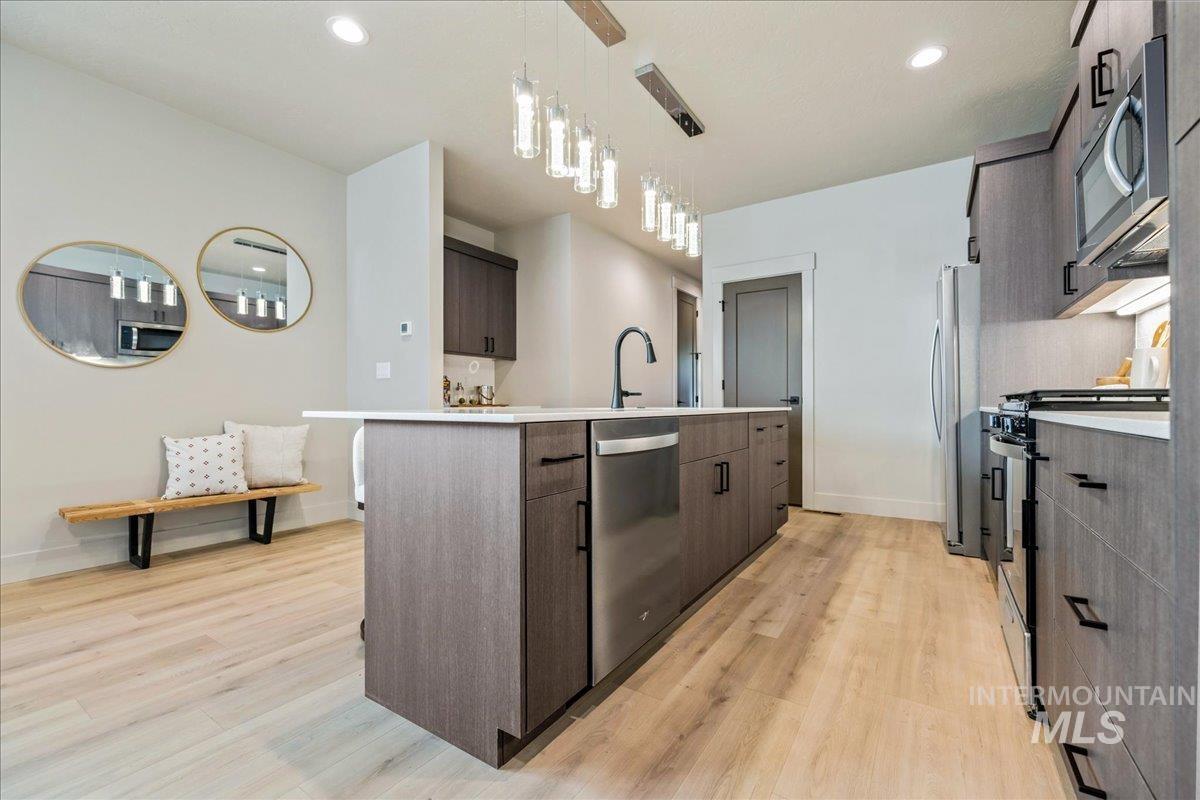 Kitchen with modern cabinets, appliances with stainless steel finishes, dark brown cabinetry, recessed lighting, and hanging light fixtures