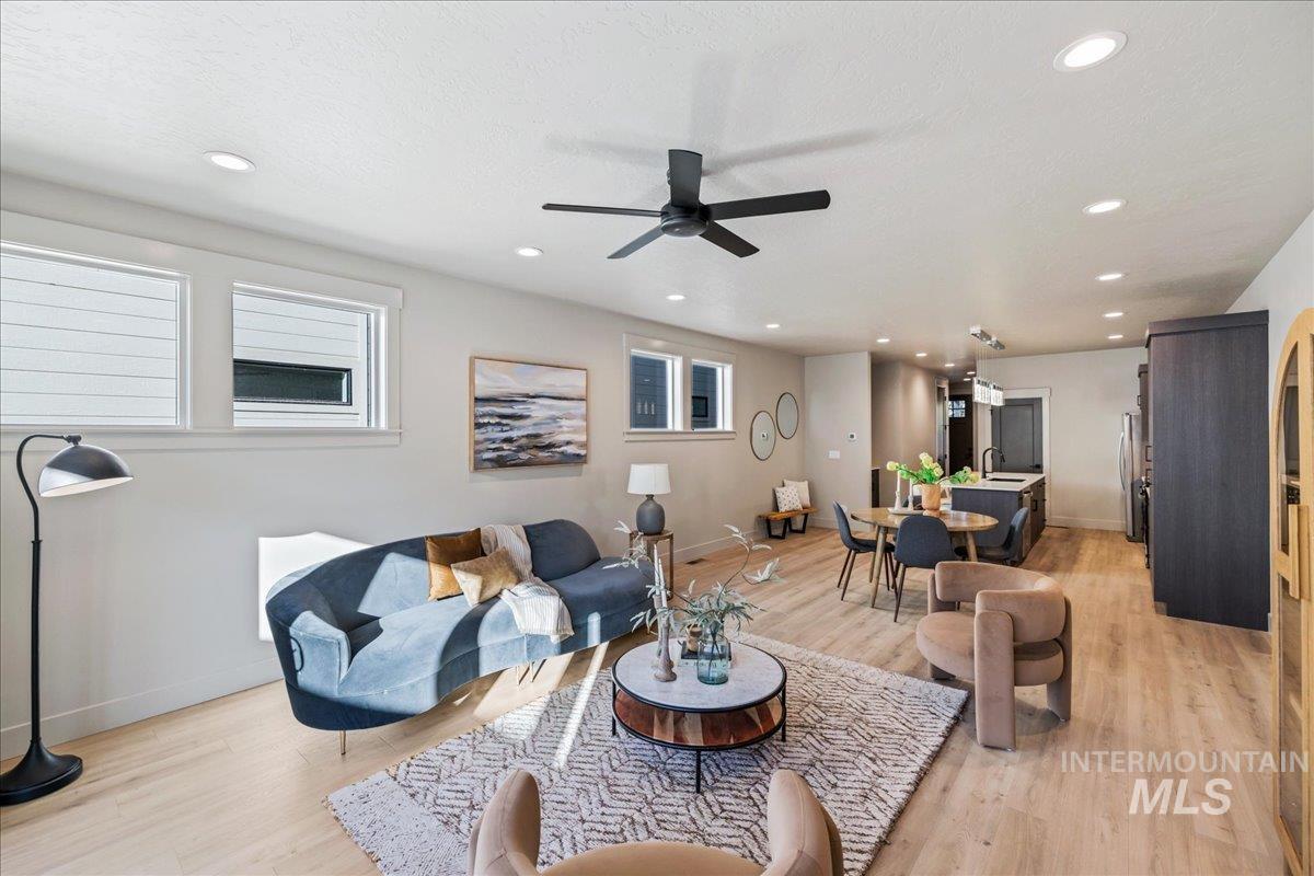 Living room with light wood-style flooring, recessed lighting, a ceiling fan, and plenty of natural light