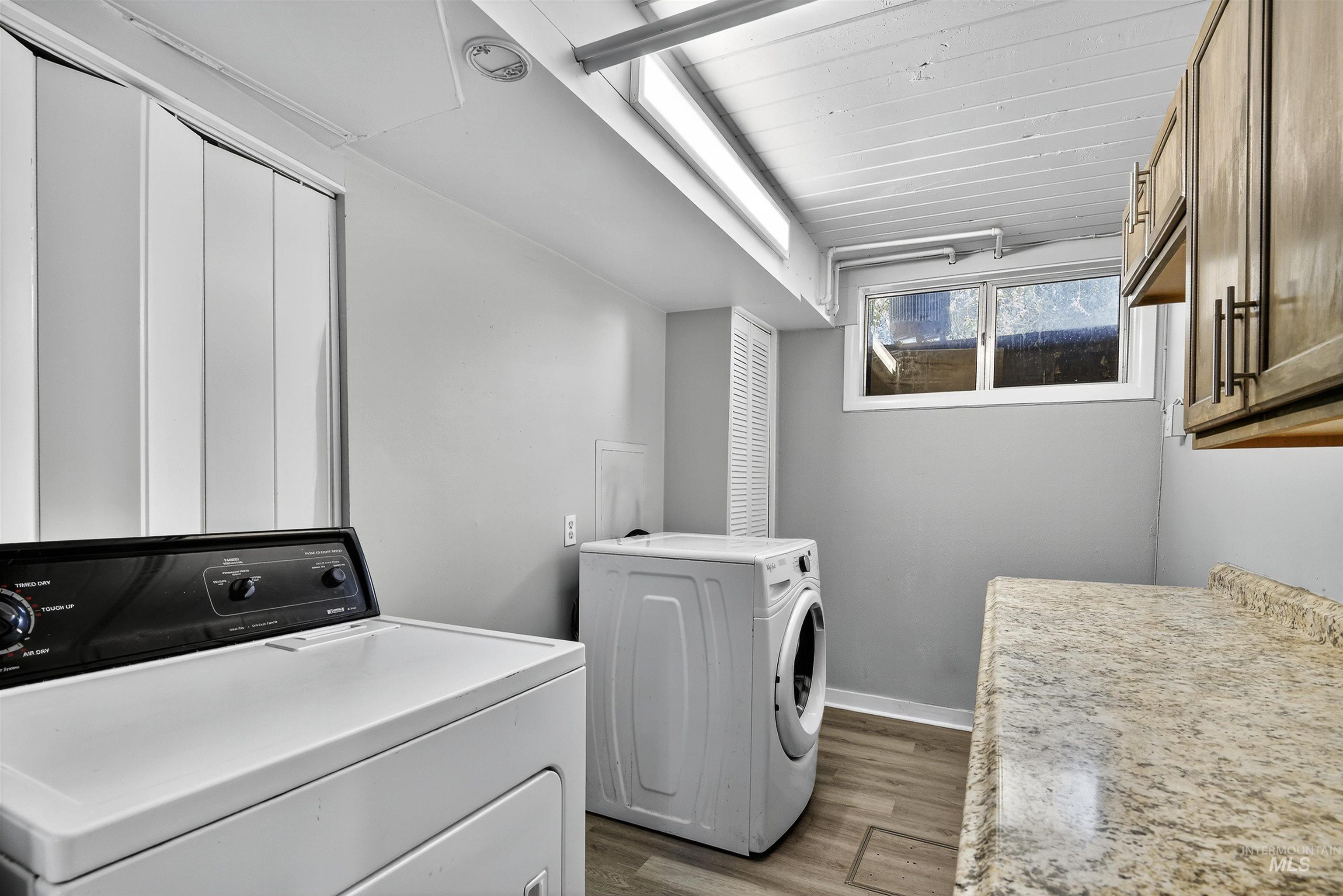 Laundry area featuring dark wood-type flooring, separate washer and dryer, and cabinet space