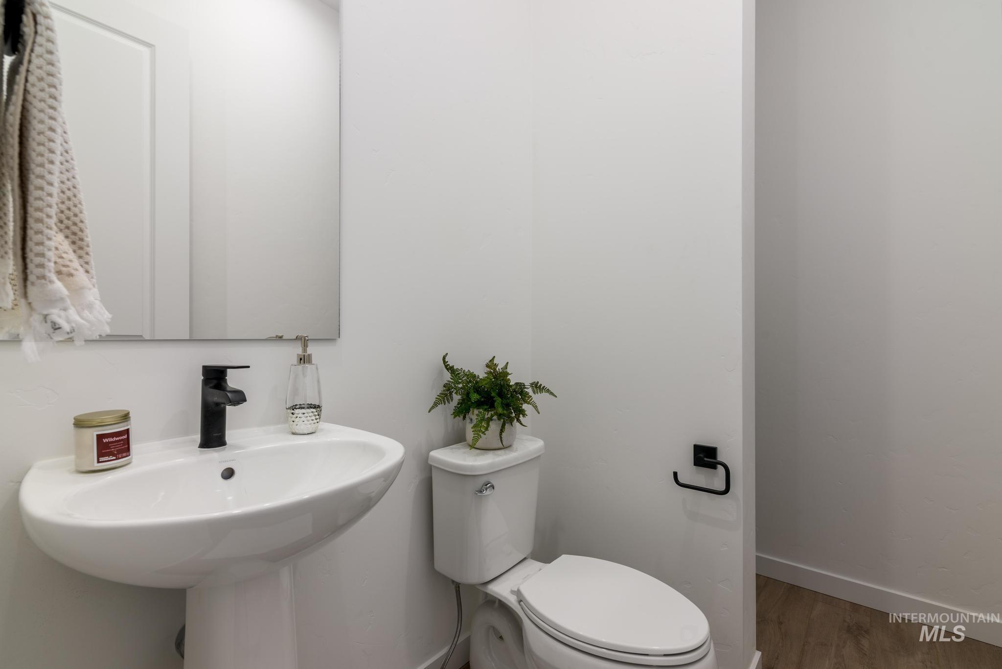 Half bath with toilet and wood finished floors