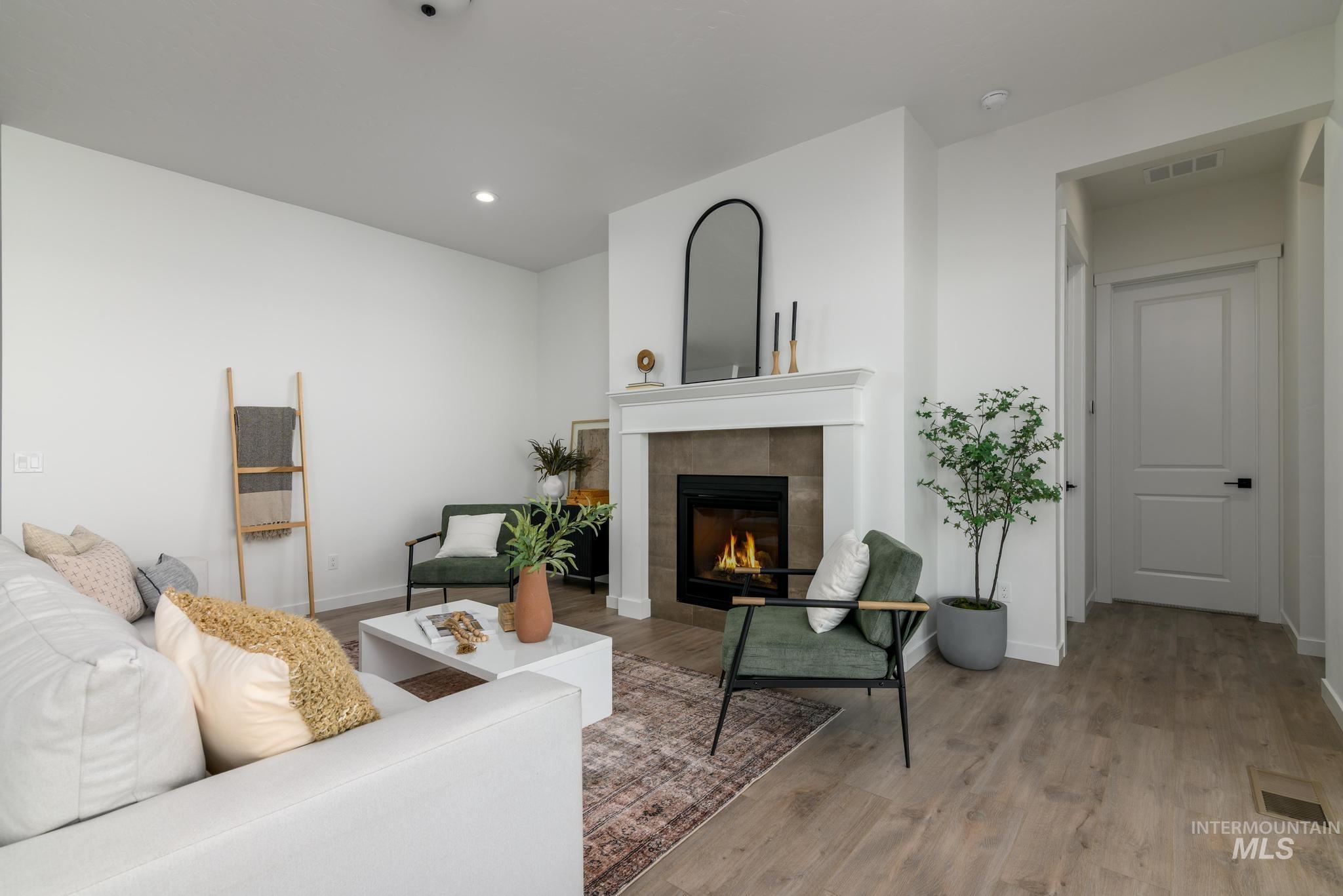 Living room featuring light wood-style floors, a tile fireplace, and recessed lighting
