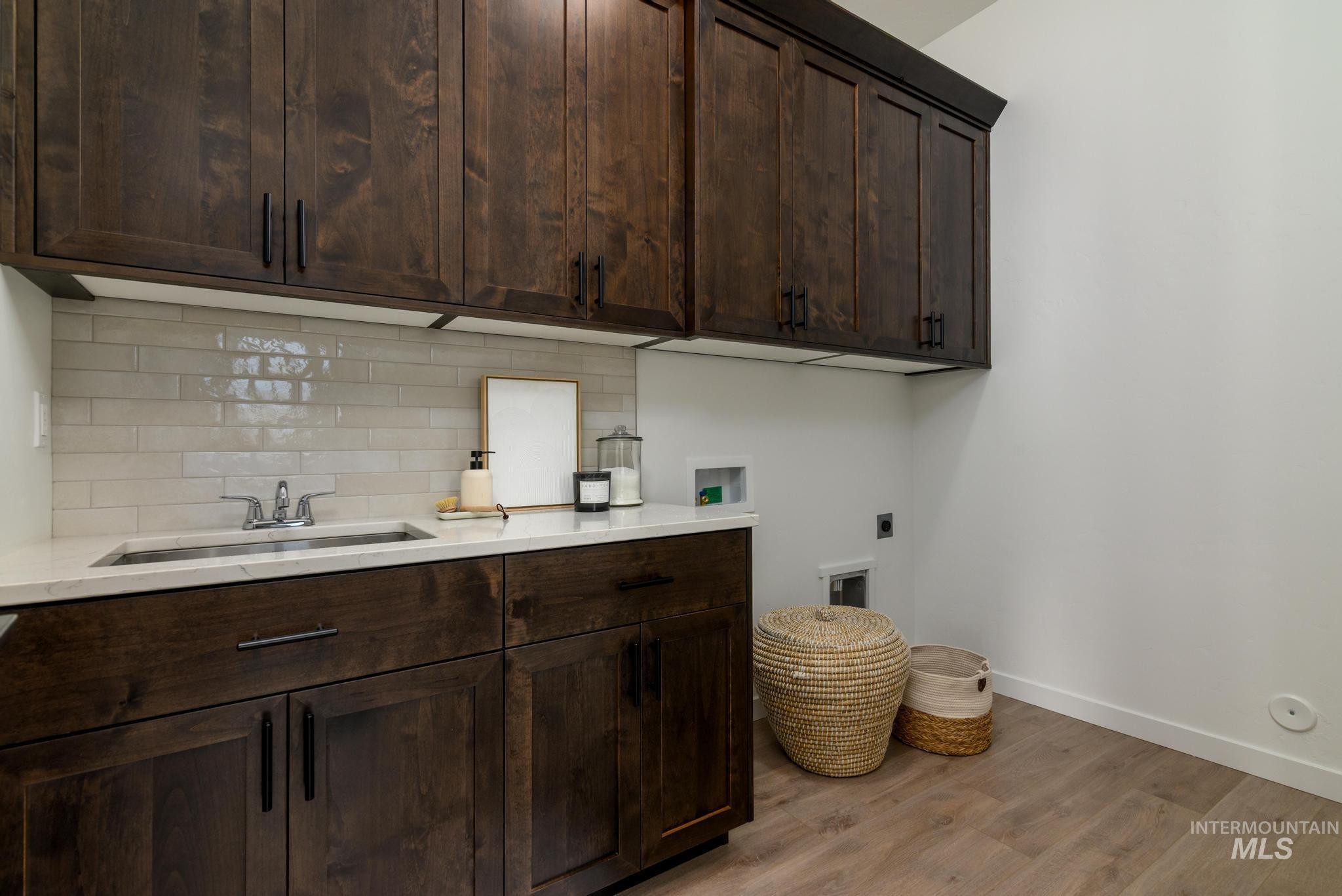 Washroom with cabinet space, electric dryer hookup, light wood-style flooring, and hookup for a washing machine