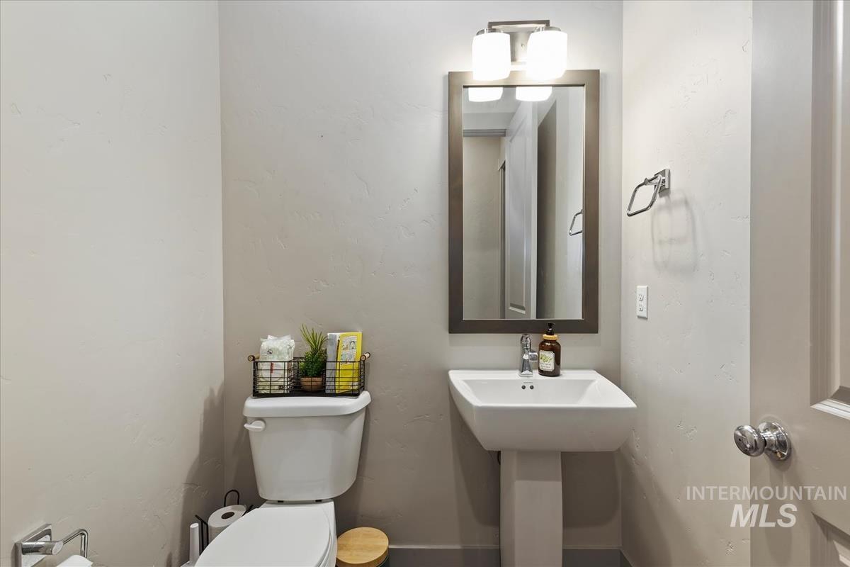 Powder room featuring a pedestal sink, framed mirror, and two-light vanity fixture