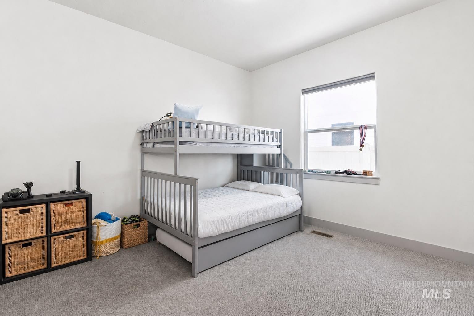 Bright room featuring a large window, light gray carpeting, and crisp white walls