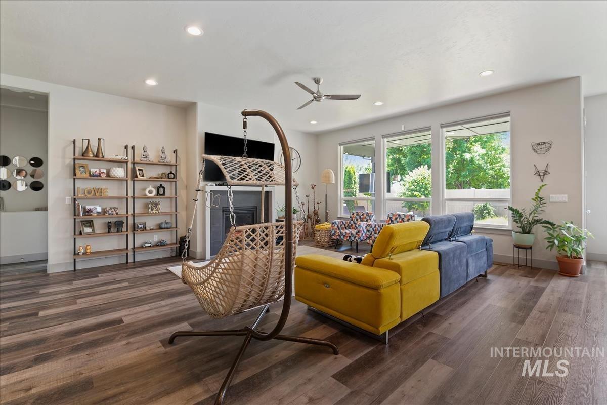 Spacious living area featuring wood-finish flooring, a fireplace with a dark surround, recessed lighting, and expansive windows