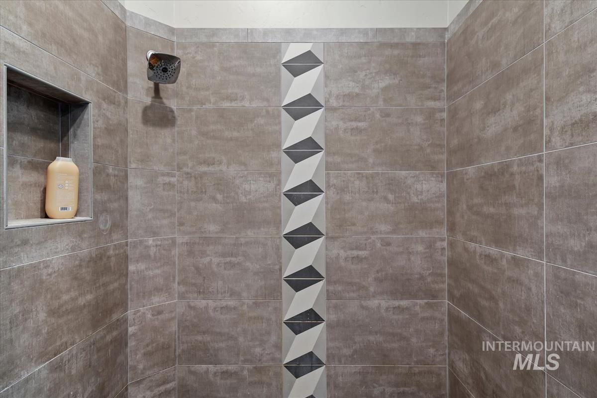 Tiled shower with a vertical mosaic accent strip, built-in niche, and square shower head