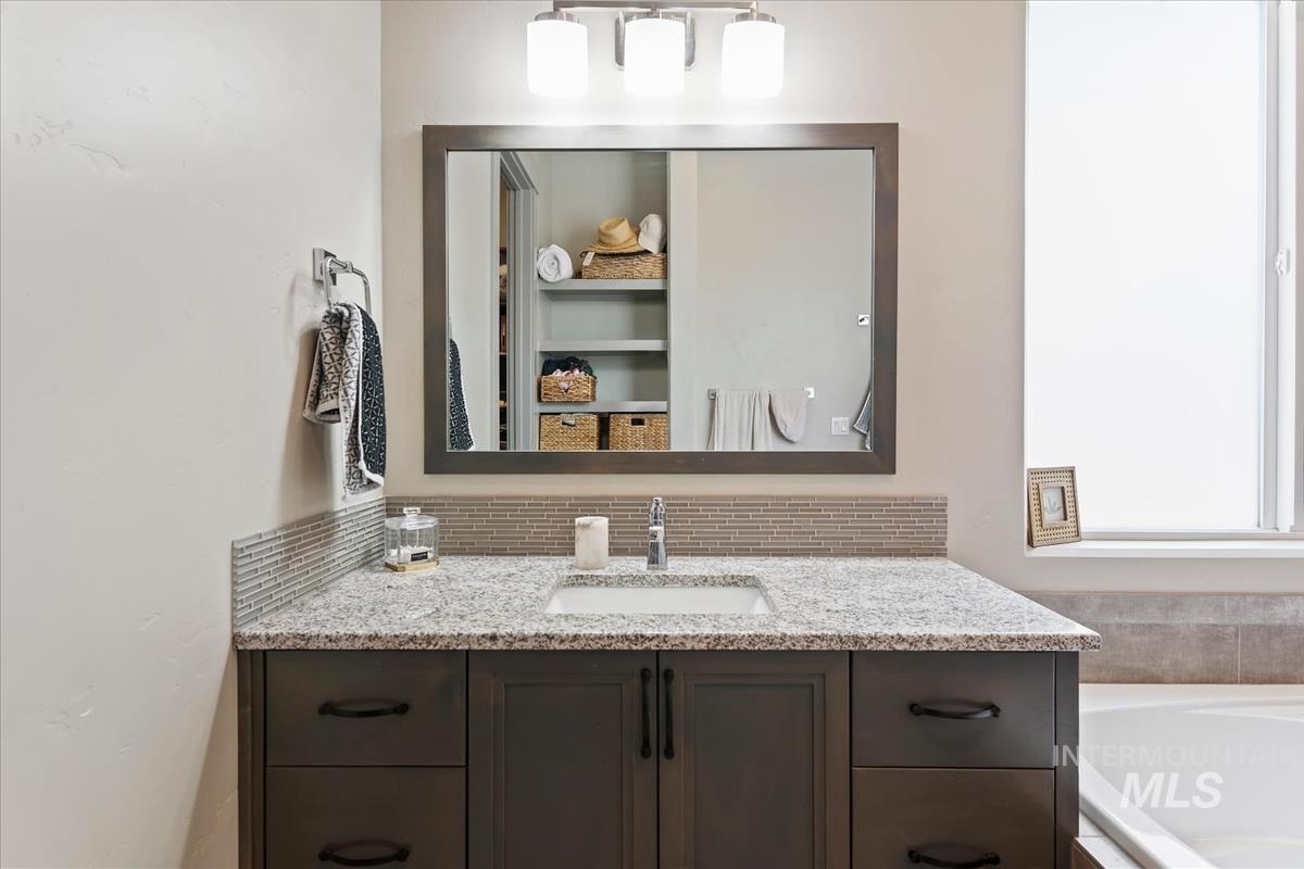 Vanity with a granite-style countertop, undermount sink, and dark wood-finish cabinetry