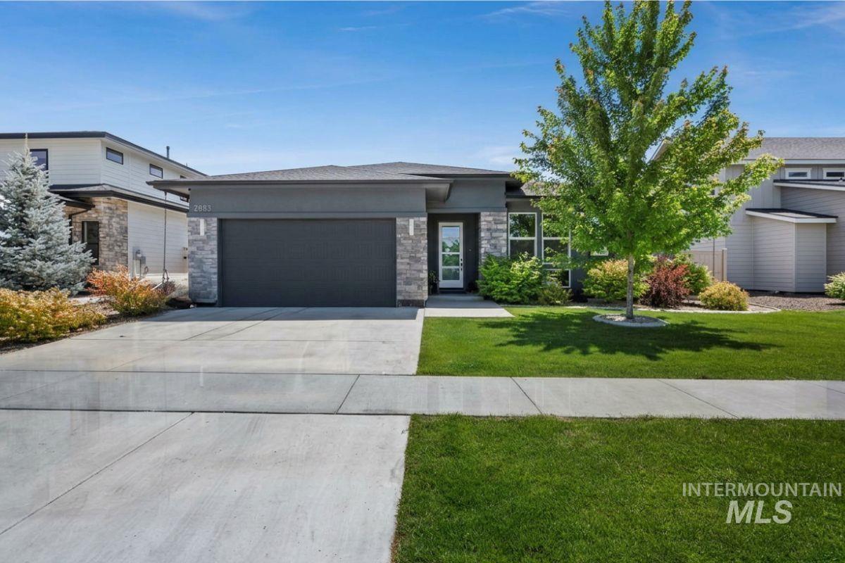 Contemporary single-story exterior featuring a dark gray facade with stone accents, a two-car garage, and a concrete driveway