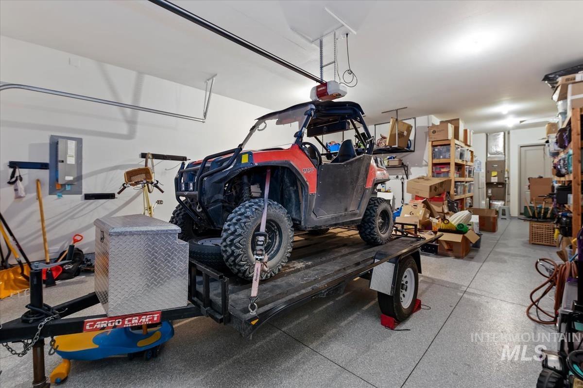 Spacious garage featuring a durable epoxy-coated floor, overhead door, and ceiling-mounted garage door opener