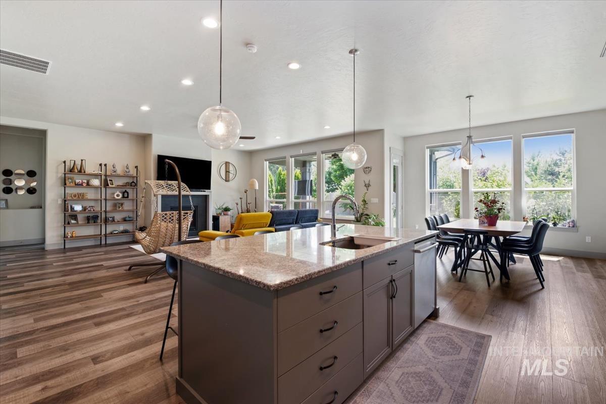 Gourmet kitchen island with an undermount sink and pendant lighting, featuring wood-finish flooring throughout