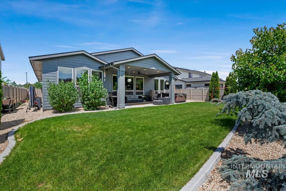 Spacious backyard featuring a manicured lawn, a covered patio, and established landscaping