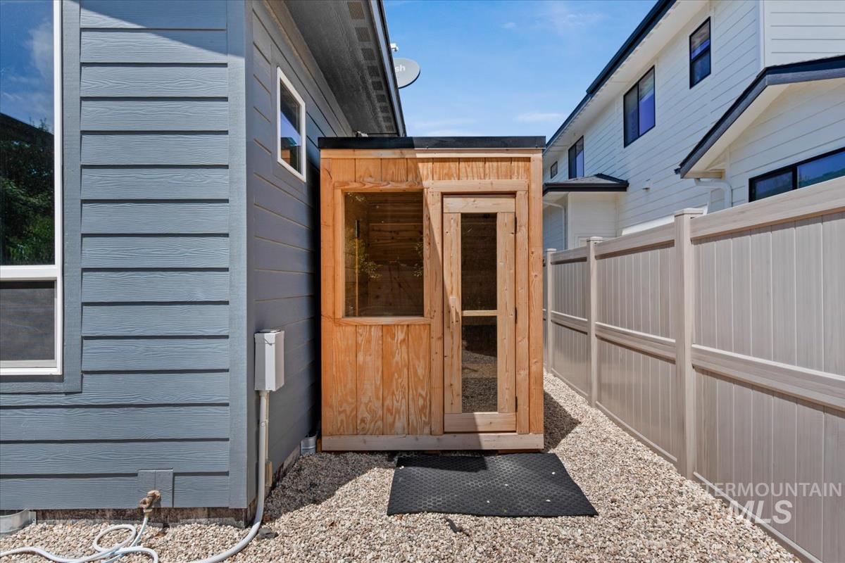 Enclosed side yard featuring a light wood-finish shed, gravel ground cover, and a privacy fence