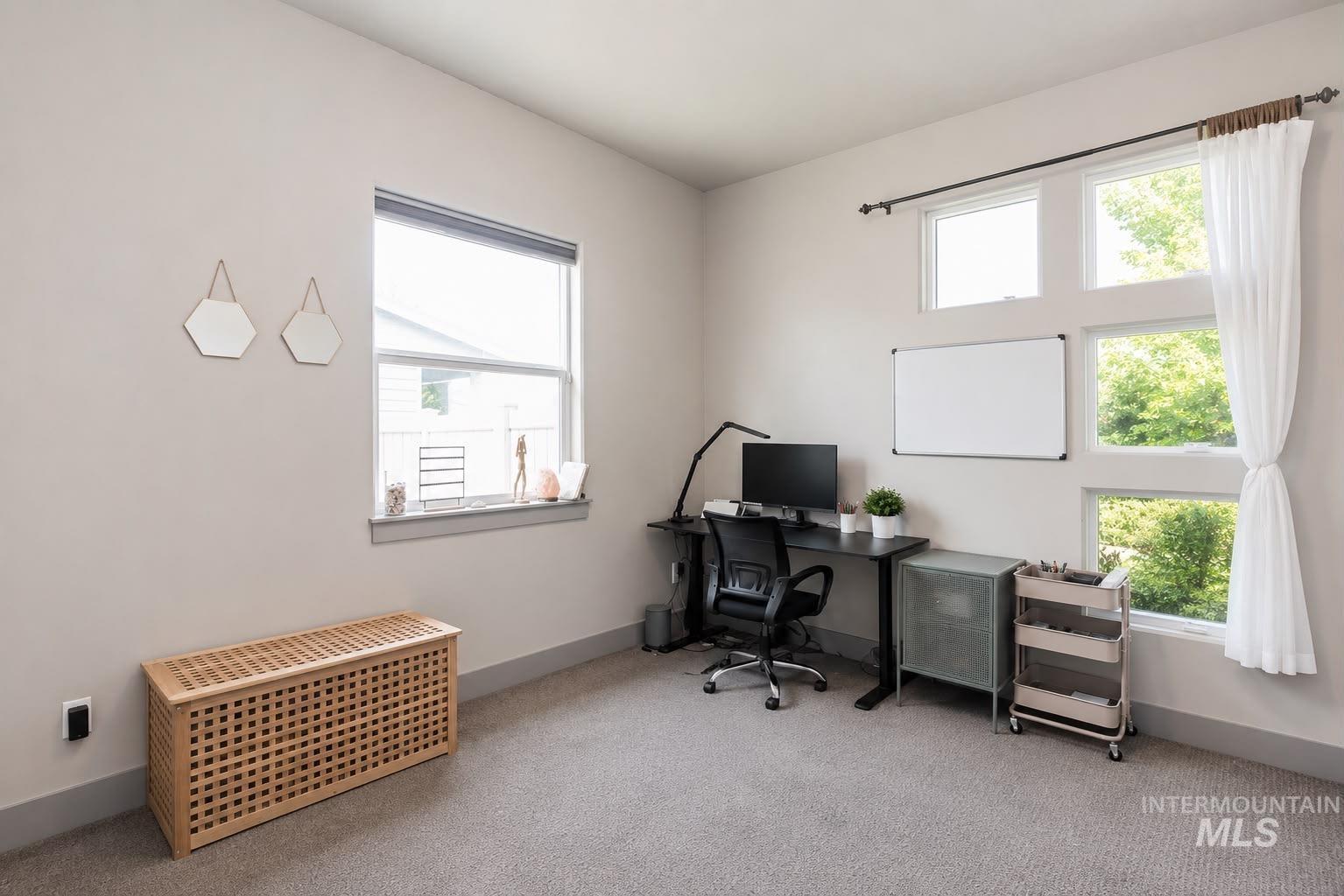 Room featuring multiple windows, light gray walls, and gray carpeting