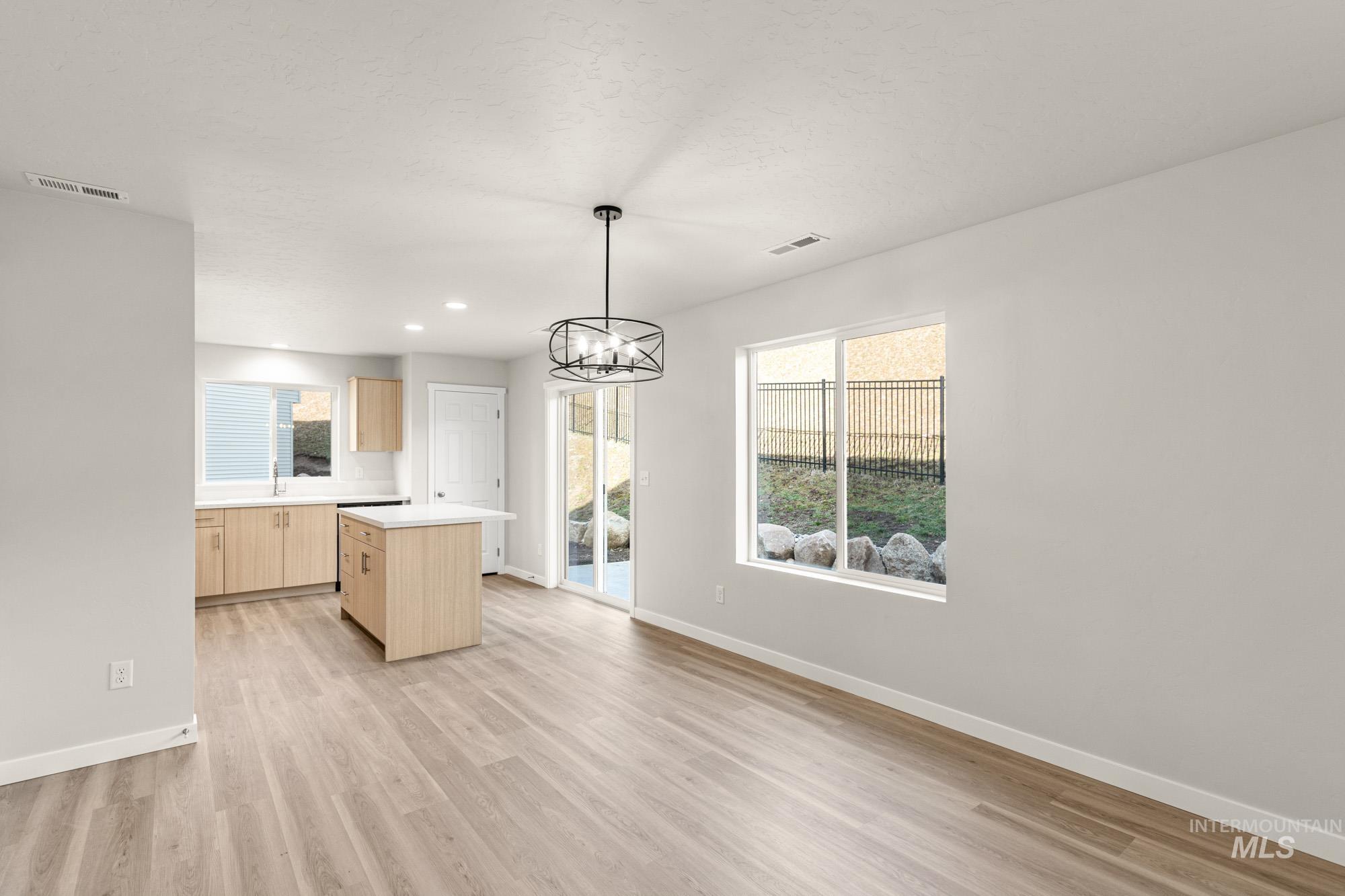 Kitchen with light wood finish cabinets, light countertops, a center island, a chandelier, and light wood-style floors