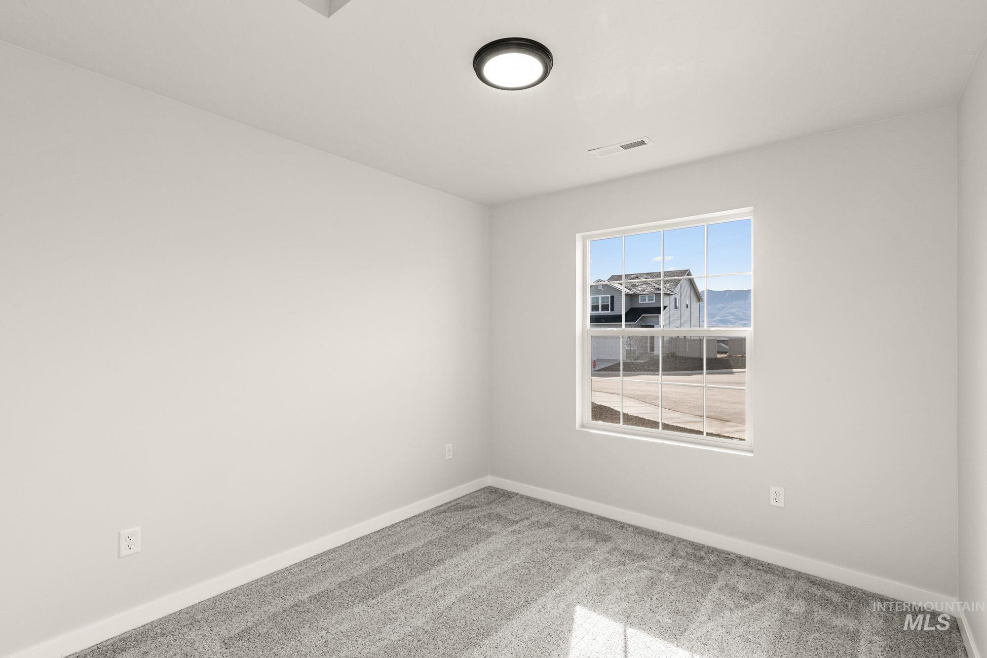 Spare room with light colored carpet and baseboards