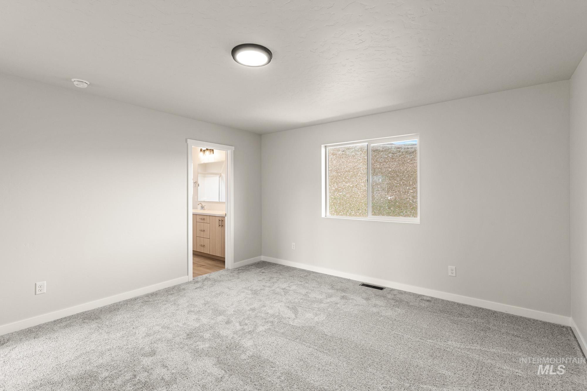 Unfurnished bedroom with light colored carpet and ensuite bath