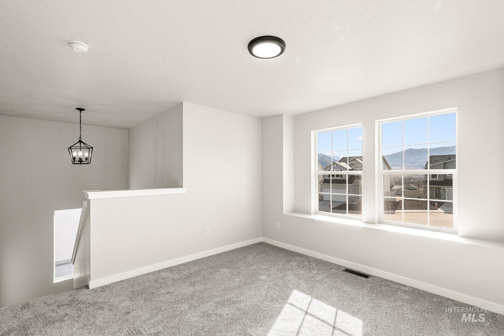 Spare room with light colored carpet and hanging lights