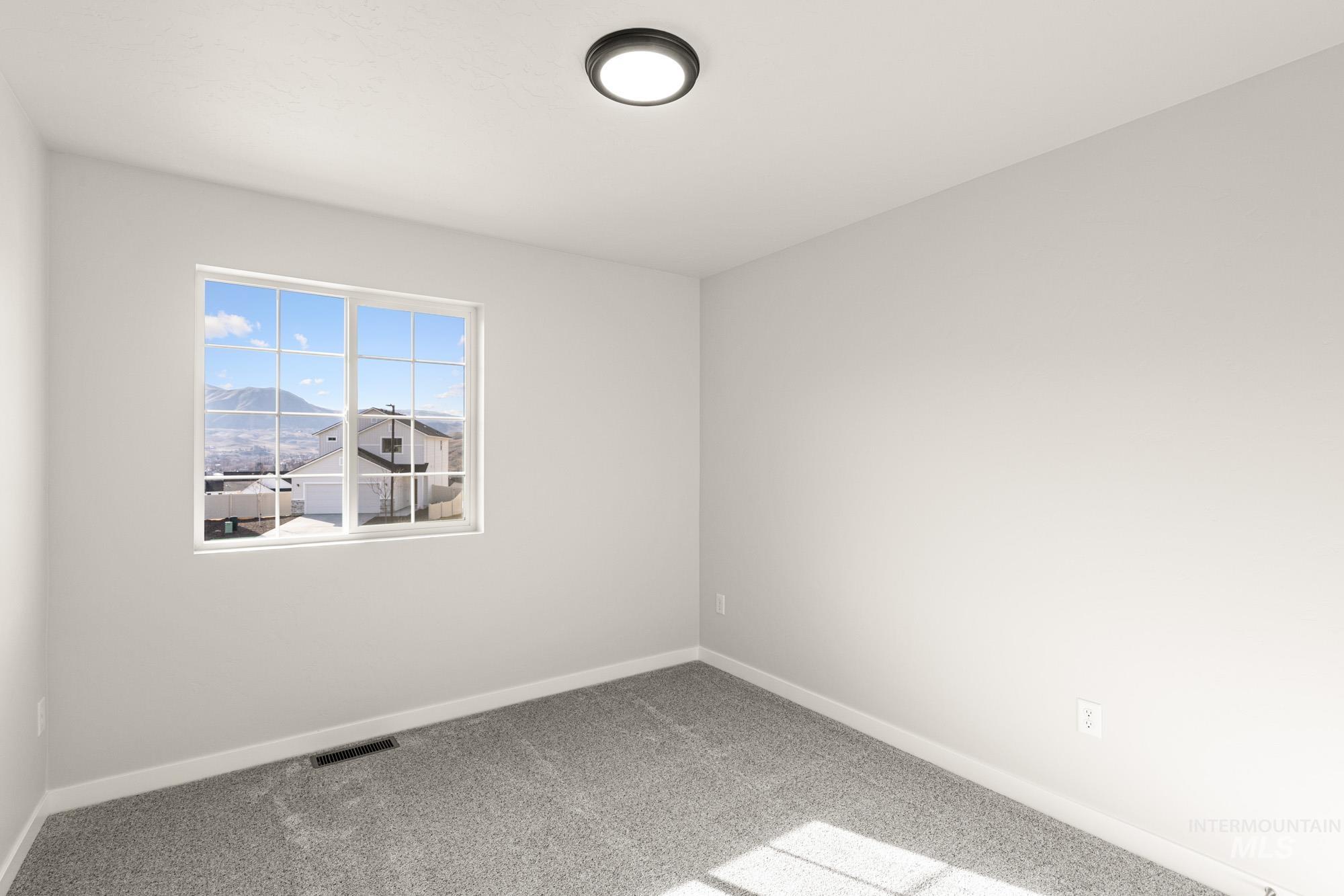 Empty room with light colored carpet and baseboards