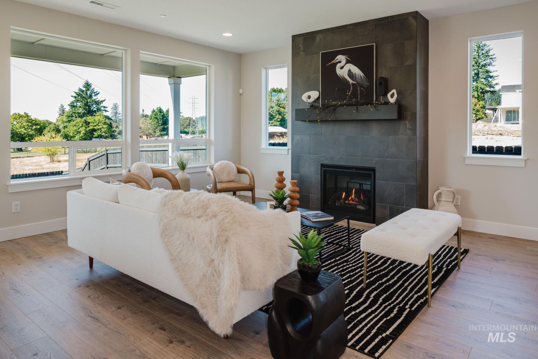Living room featuring light wood-style flooring, a tiled fireplace, and recessed lighting
