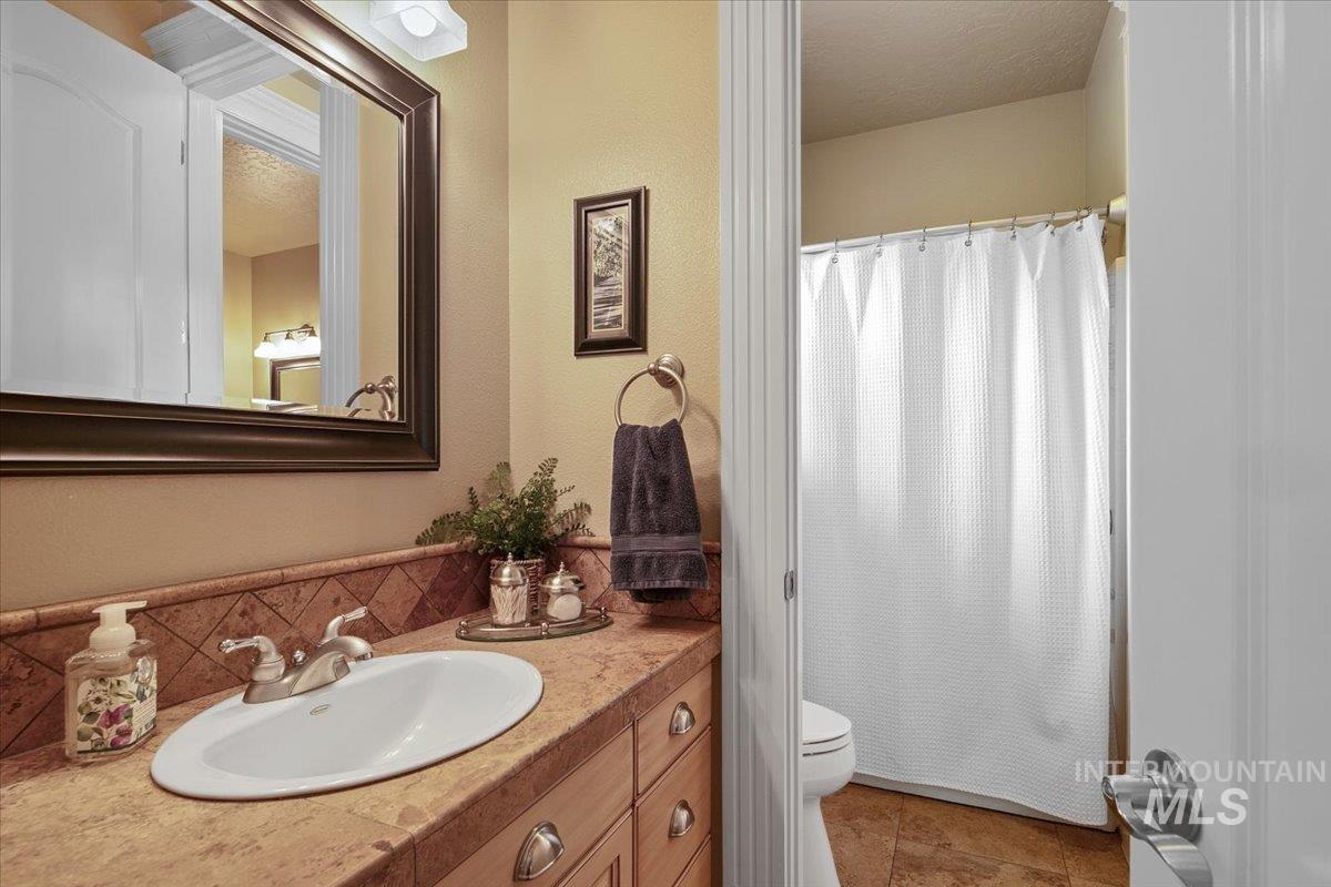 Full bathroom with vanity, tile patterned floors, curtained shower, a textured ceiling, and tasteful backsplash