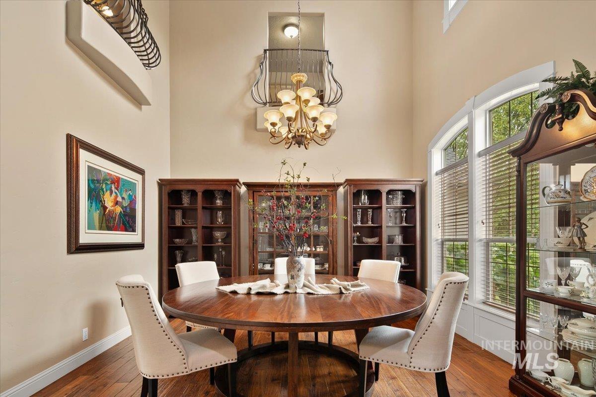 Dining space with plenty of natural light, hardwood / wood-style flooring, a high ceiling, and a chandelier