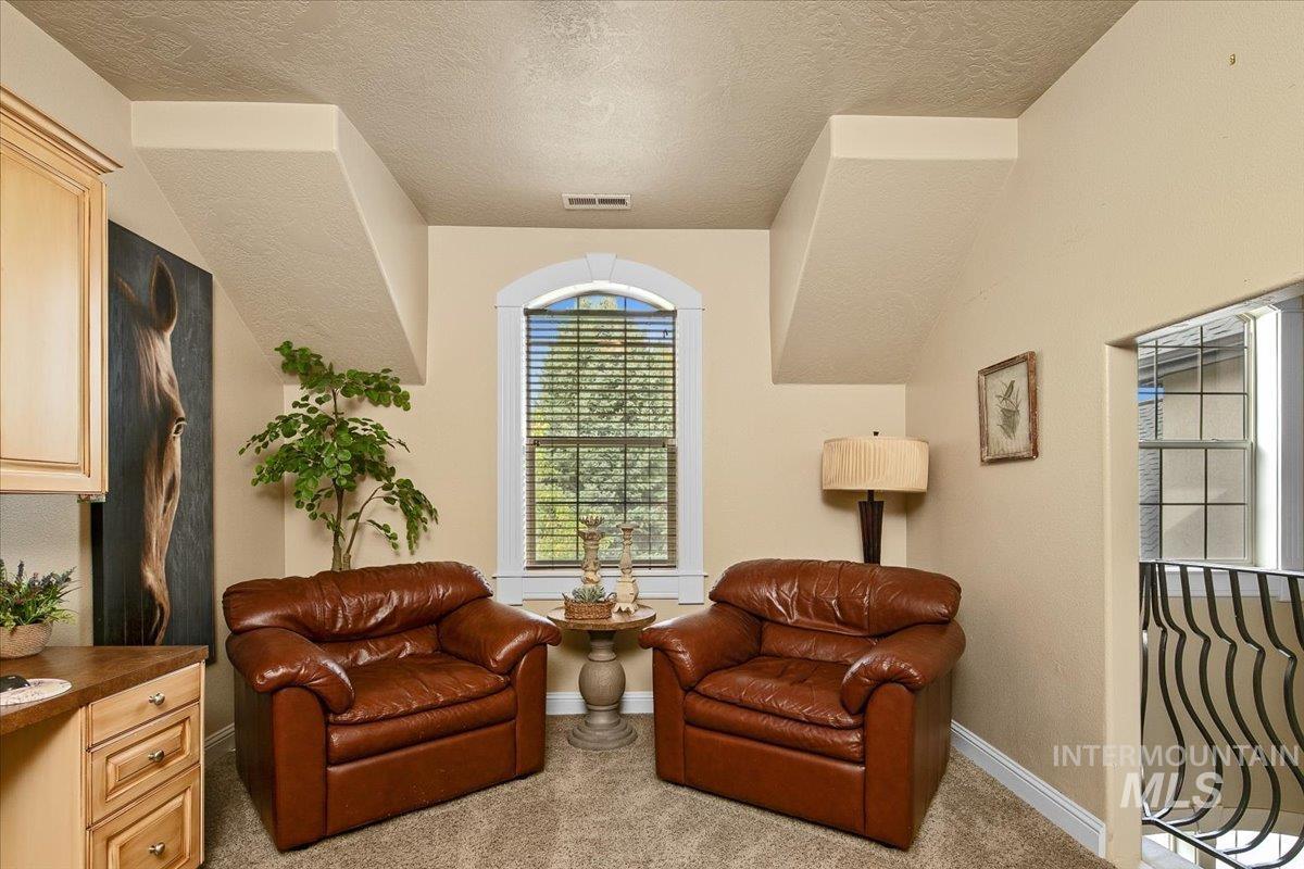Living area featuring light colored carpet and a textured ceiling