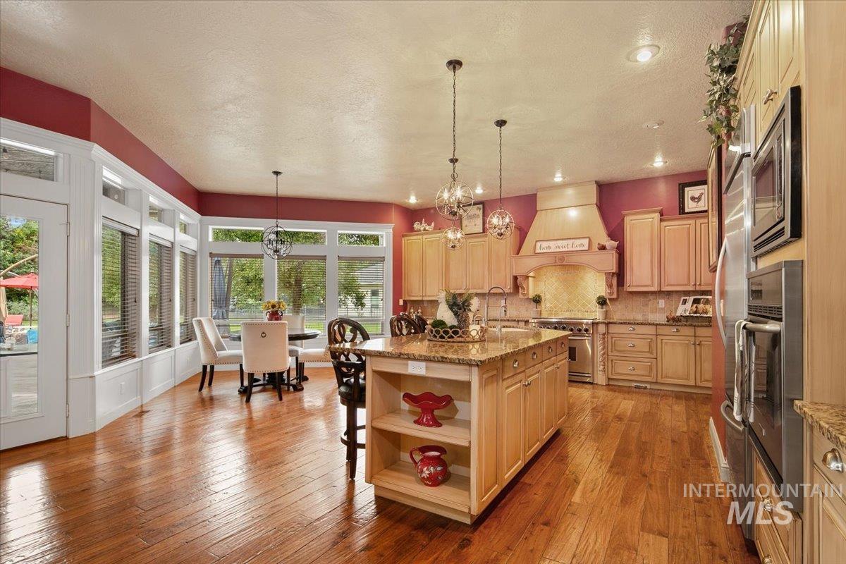 Kitchen with decorative backsplash, open shelves, light stone countertops, light wood-type flooring, and appliances with stainless steel finishes