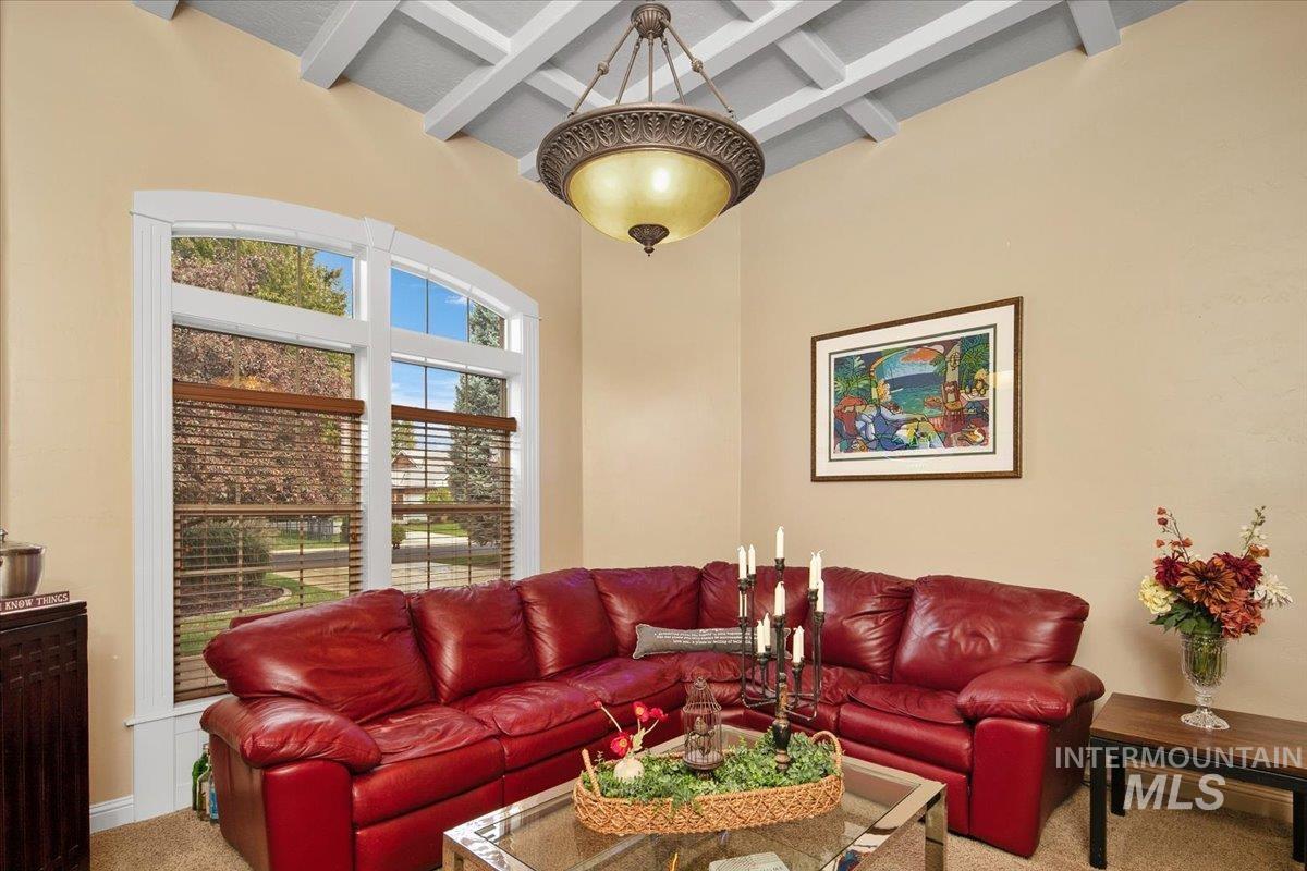 Living area featuring beam ceiling, carpet, a towering ceiling, and coffered ceiling