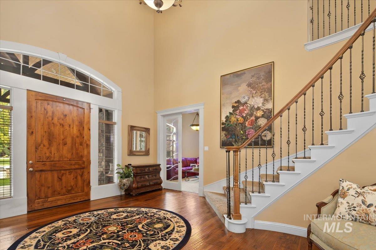 Foyer with stairway, wood finished floors, and a high ceiling
