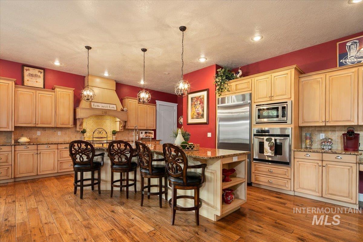 Kitchen featuring decorative backsplash, a kitchen breakfast bar, open shelves, built in appliances, and a center island with sink