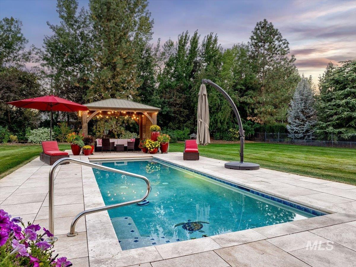 Outdoor pool with a gazebo, a patio, outdoor lounge area, and view of wooded area